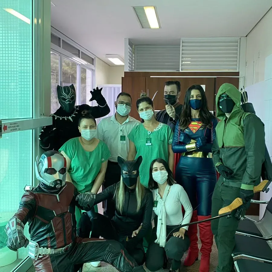Voluntários fantasiados junto à equipe de saúde, usando máscaras